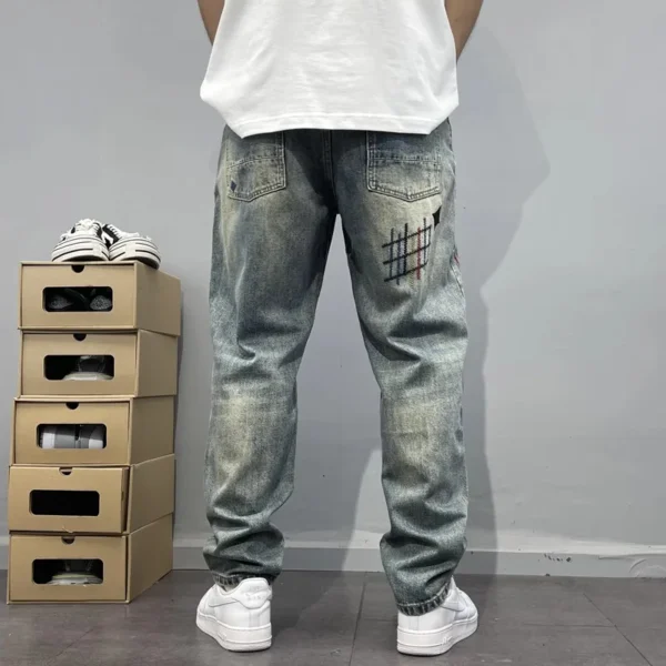 Jean homme tendance, audacieux et élégant, orné de broderies et d'imprimés patchwork, coupe droite ample.