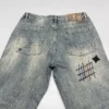 Jean homme tendance, audacieux et élégant, orné de broderies et d'imprimés patchwork, coupe droite ample.