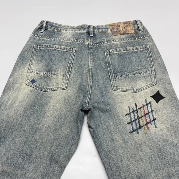 Jean homme tendance, audacieux et élégant, orné de broderies et d'imprimés patchwork, coupe droite ample.